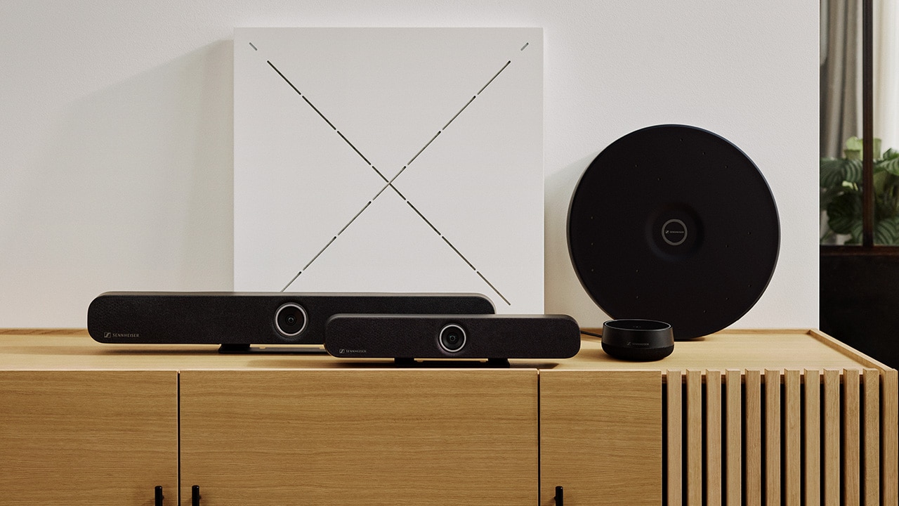 Modern office setup with two black rectangular speakers, a circular device, and a square panel with an X on a wooden cabinet.